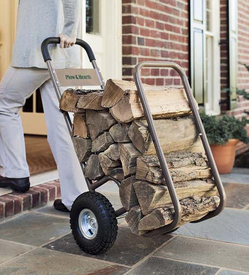A person climbs up a front step with a Rolling Log Cart full of firewood