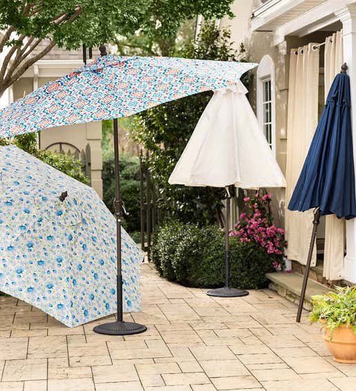 Several outdoor umbrellas with colorful canopies sit on a back patio