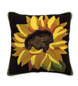 A hand hooked throw pillow with the image of a large sunflower on a black background.