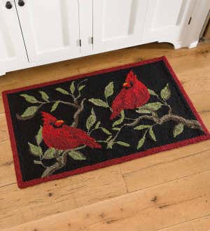 A hooked outdoor rug with two red cardinals on it