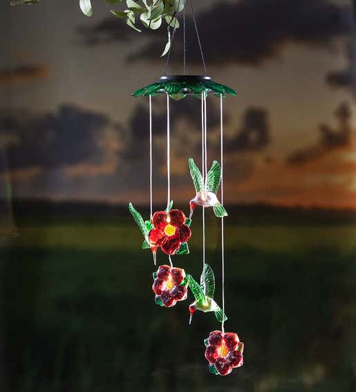 A solar mobile of hummingbirds and red flowers shines in the dark