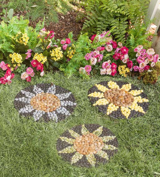 A set of three sunflower stepping stones sit beside a flower bed