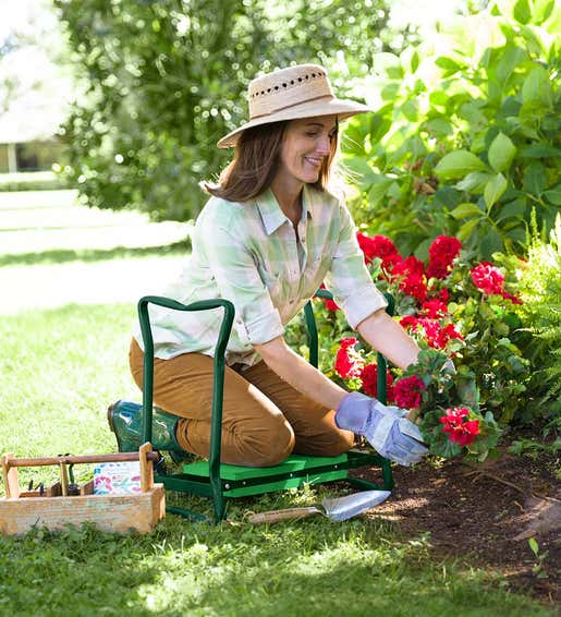 Image of a woman planting flowers while using a padded folding Garden Kneeler. Shop Garden Tools