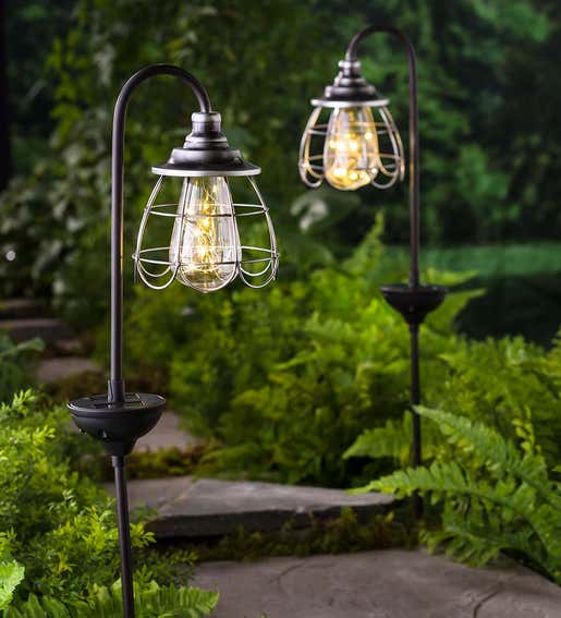 A pair of two solar firefly lantern path lights in a garden