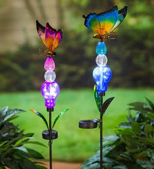 Image of a pair of colorful glowing garden stakes with butterflies on top. Shop Solar Accents