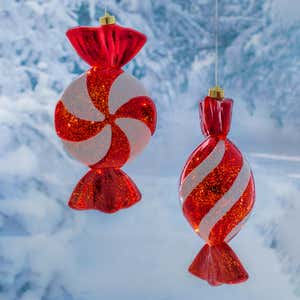 A lighted red and white candy ornament hangs outdoors