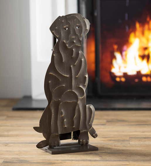 A fireplace tool set shaped like a Labrador dog sits beside a blazing fireplace